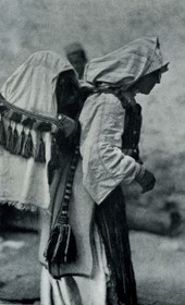 HAB14: “Peasant woman at Saint Anne’s [Shën Ana] with a cradle on her back. The wooden cradle is covered with a veil to protect the child from the flies” (Photo: Hugo Bernatzik, 1929).